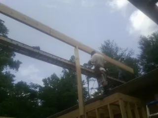 Carpenter setting a ridge beam over a new addition frame — Ice Dam Removal by Roofing Brothers in Soldier