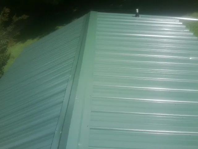 New green metal panels meeting at the ridge of a roof — Flat Roof Repair work by our crew in Soldier