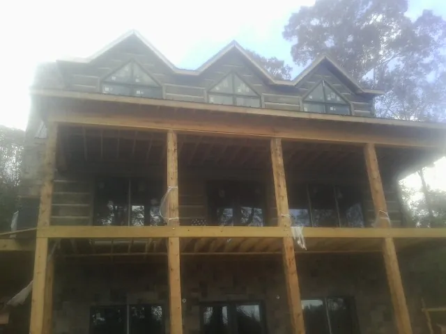 Dormers and porch framing on a large log home under construction — Roof Coating work by our crew in Soldier