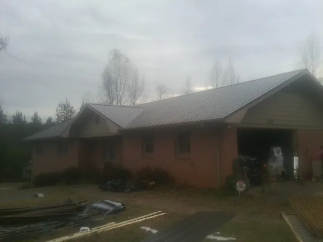 Gray metal roof on a stucco house with an attached garage in Soldier