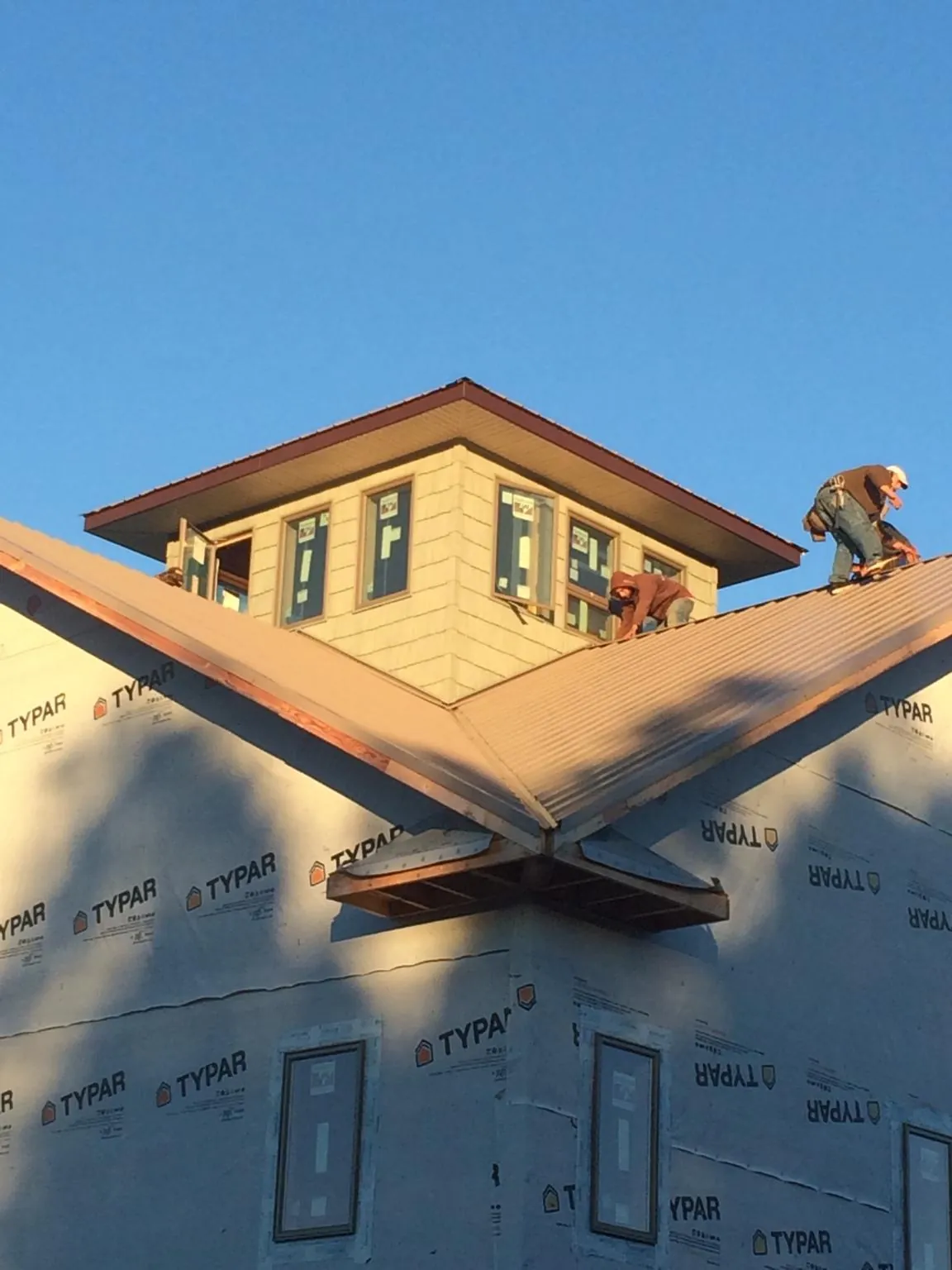 Roofers working around a rooftop cupola on a new metal roof at sunset — Roof Waterproofing in Soldier by Roofing Brothers